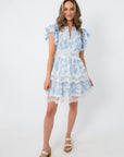 Back view of blue floral lace trim mini dress with ruffled sleeves and tiered skirt