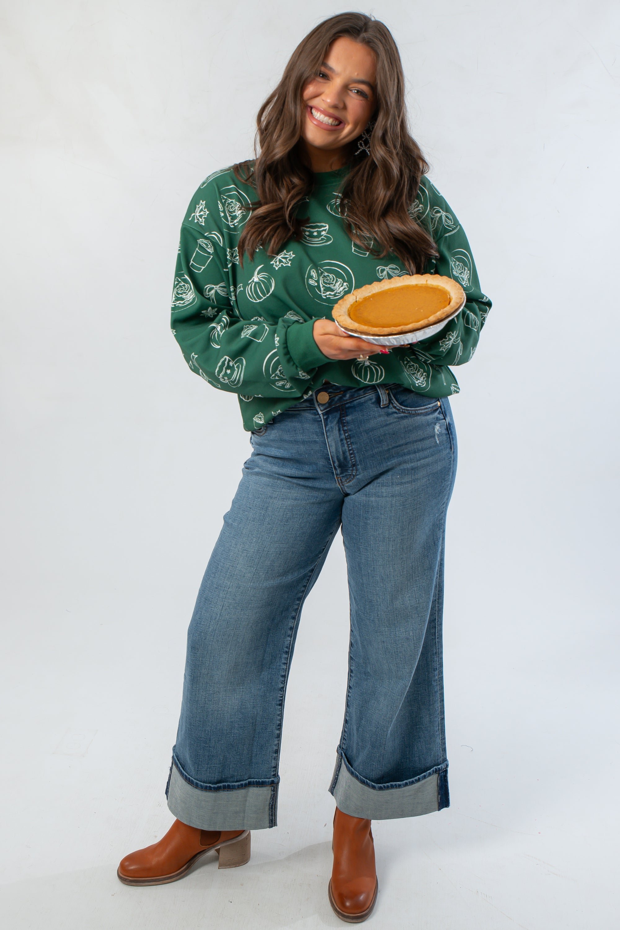 Pumpkin Pie Cutie Hunter Green Sweatshirt styled with wide-leg jeans, holding a pumpkin pie for a festive Thanksgiving outfit idea.