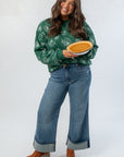 Pumpkin Pie Cutie Hunter Green Sweatshirt styled with wide-leg jeans, holding a pumpkin pie for a festive Thanksgiving outfit idea.