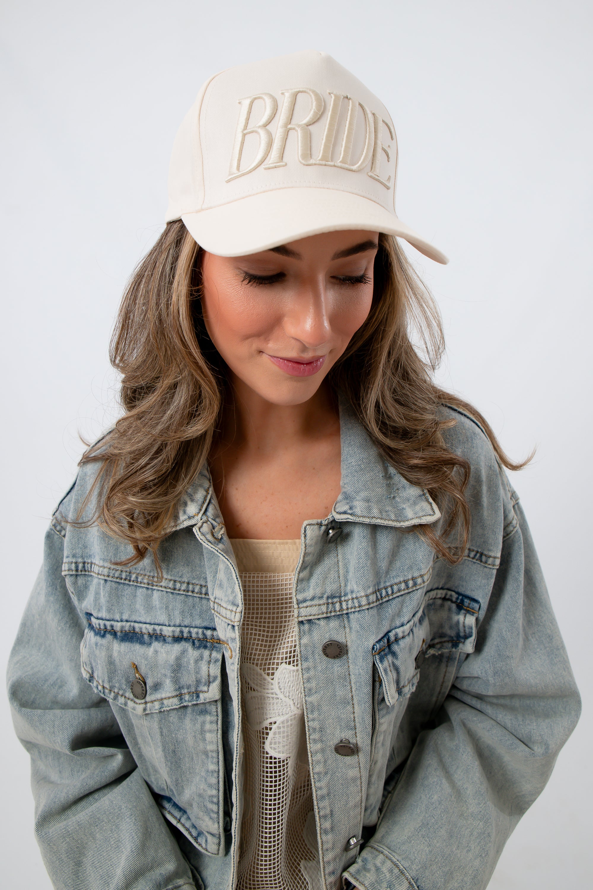 Model wearing Bride Embroidered Trucker Hat with denim jacket and floral dress for bridal accessories