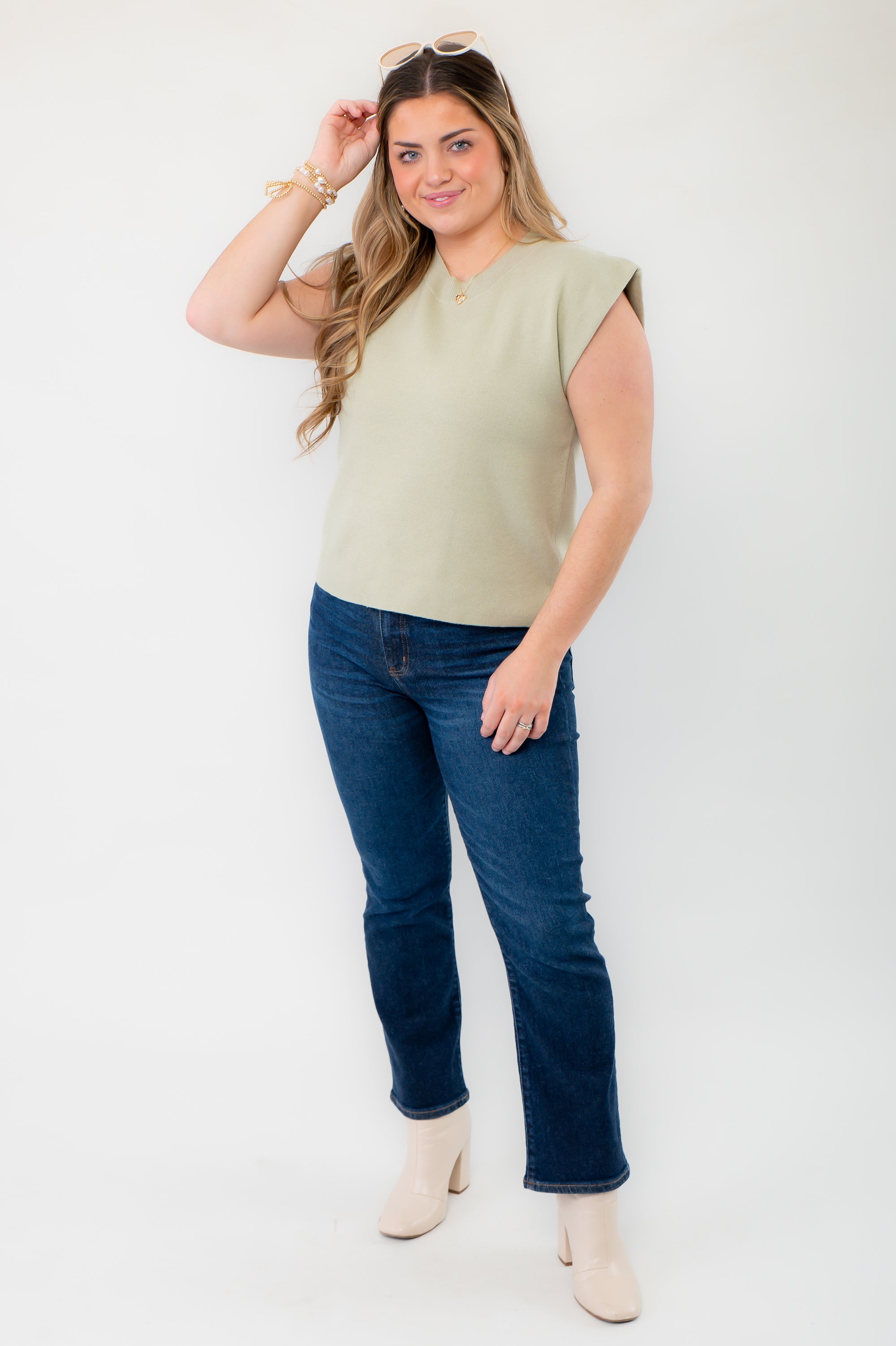 Model wearing the Dally Sage Green Muscle Sweater Tank paired with dark denim and white boots for a stylish casual outfit.