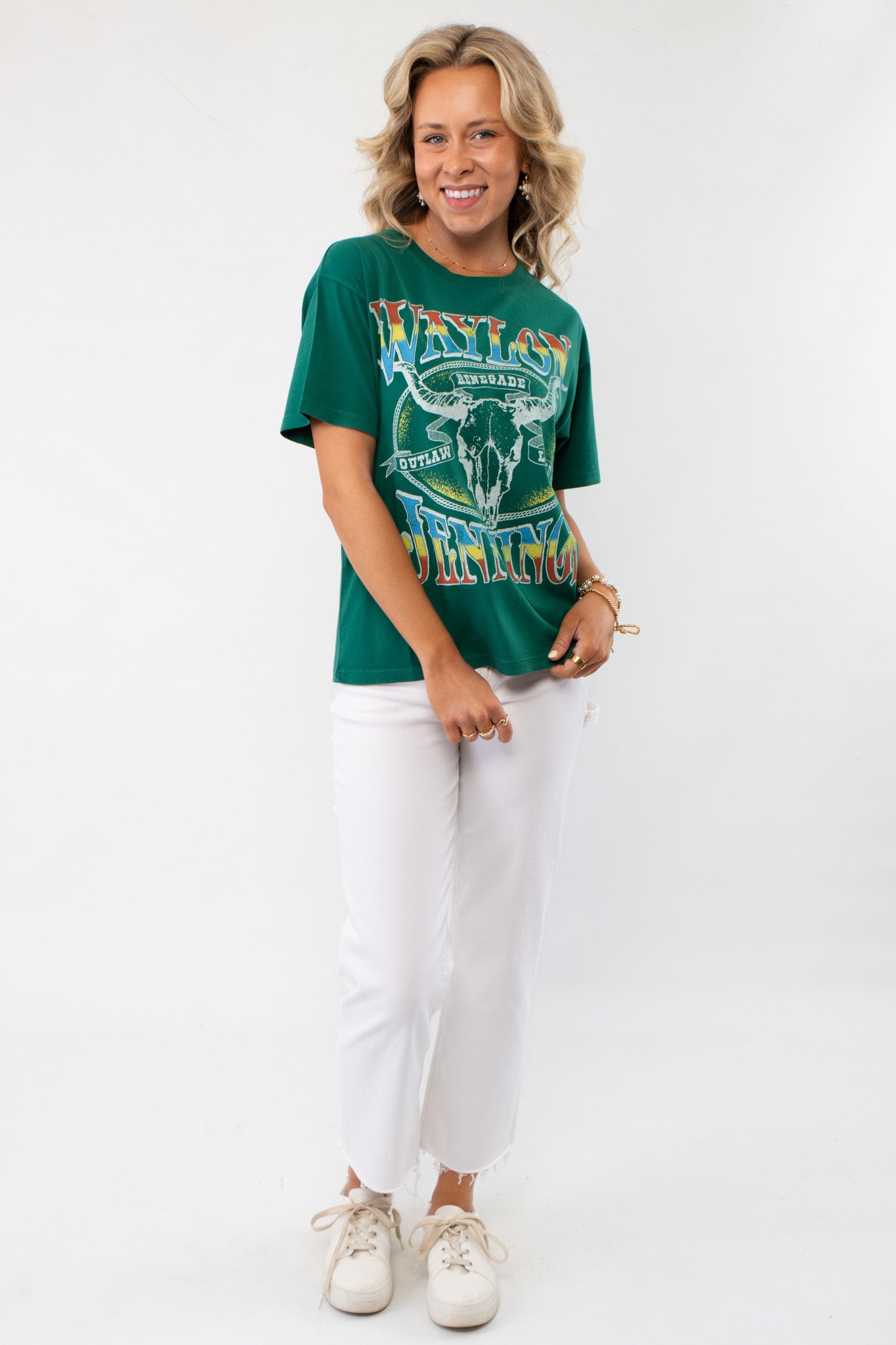 Full-body view of model wearing the Daydreamer Green Waylon Jennings Outlaw Legend Graphic Tee, paired with white jeans for a casual, stylish look.