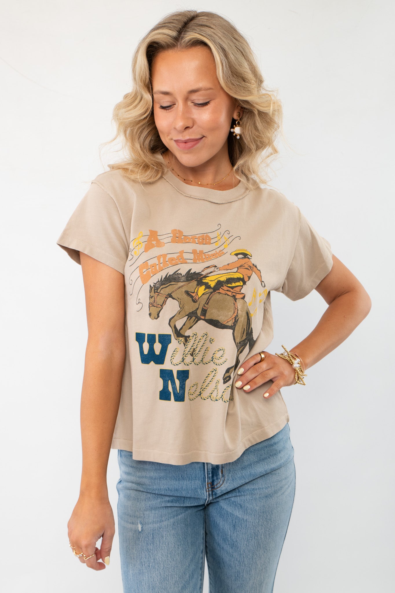 Daydreamer Willie Nelson 'A Horse Called Music' Graphic Tee in beige with vintage country-inspired artwork, styled with blue jeans.