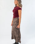 Side view of Friday Feeling Burgundy Asymmetrical Top showing stretchy fit and off-shoulder neckline, styled with a leopard skirt.