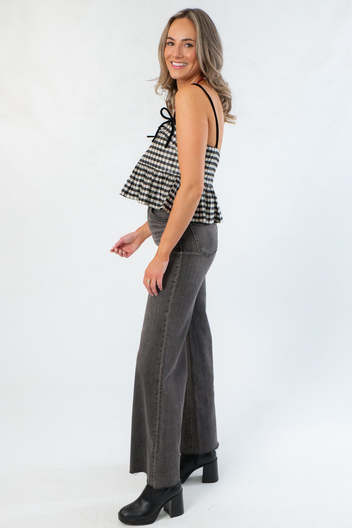 Side profile of Girly Girl Shiny Black Gingham Peplum Top showing flared hem and adjustable shoulder straps for a flattering fit.