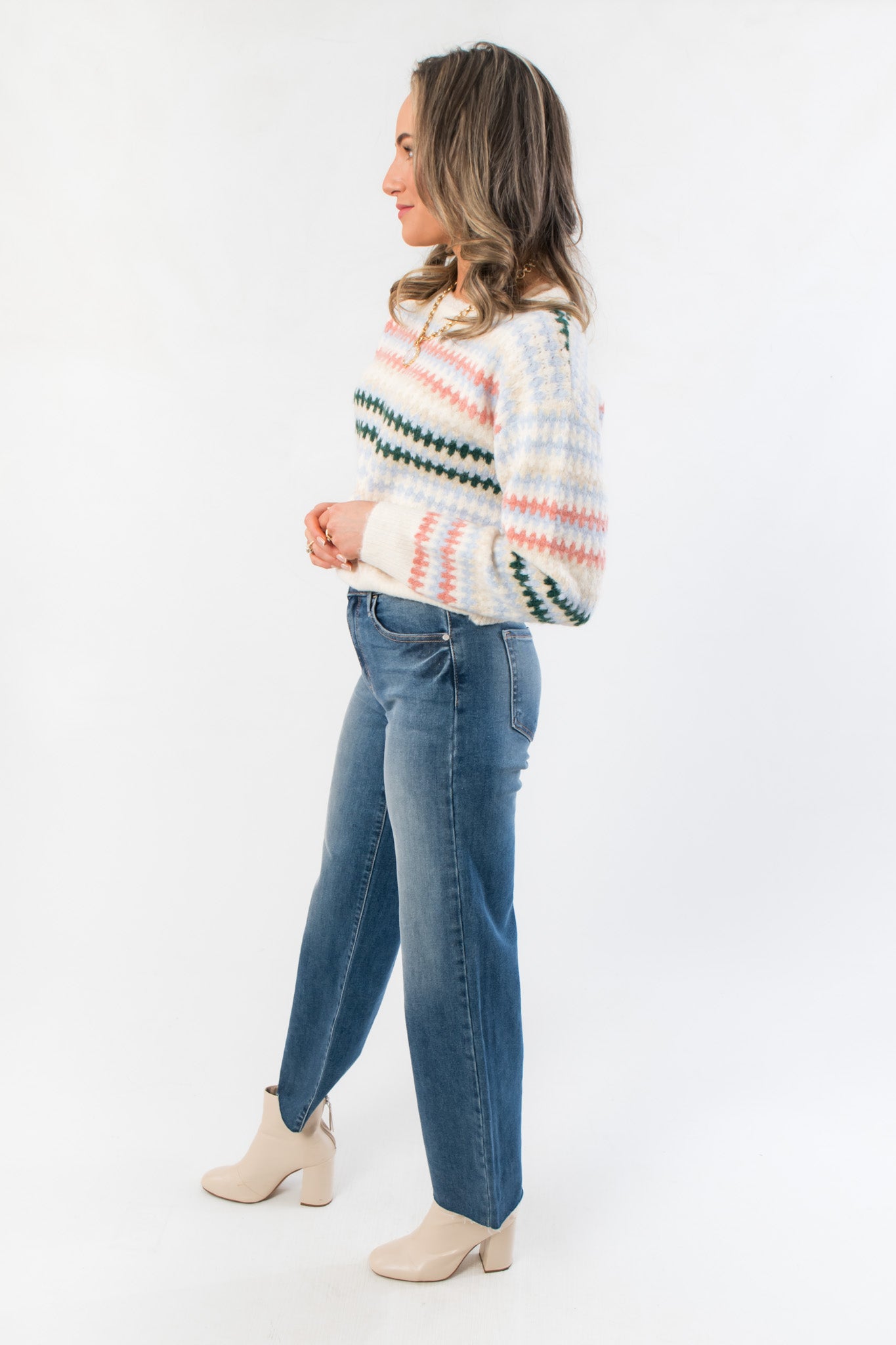 Side view of Mountain Top Stripe Knit Sweater showing pastel stripe pattern and comfortable fit, styled with casual denim and boots.