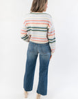 Back view of Mountain Top Stripe Knit Sweater with multi color stripe design and ribbed hem, paired with high-waisted denim jeans.
