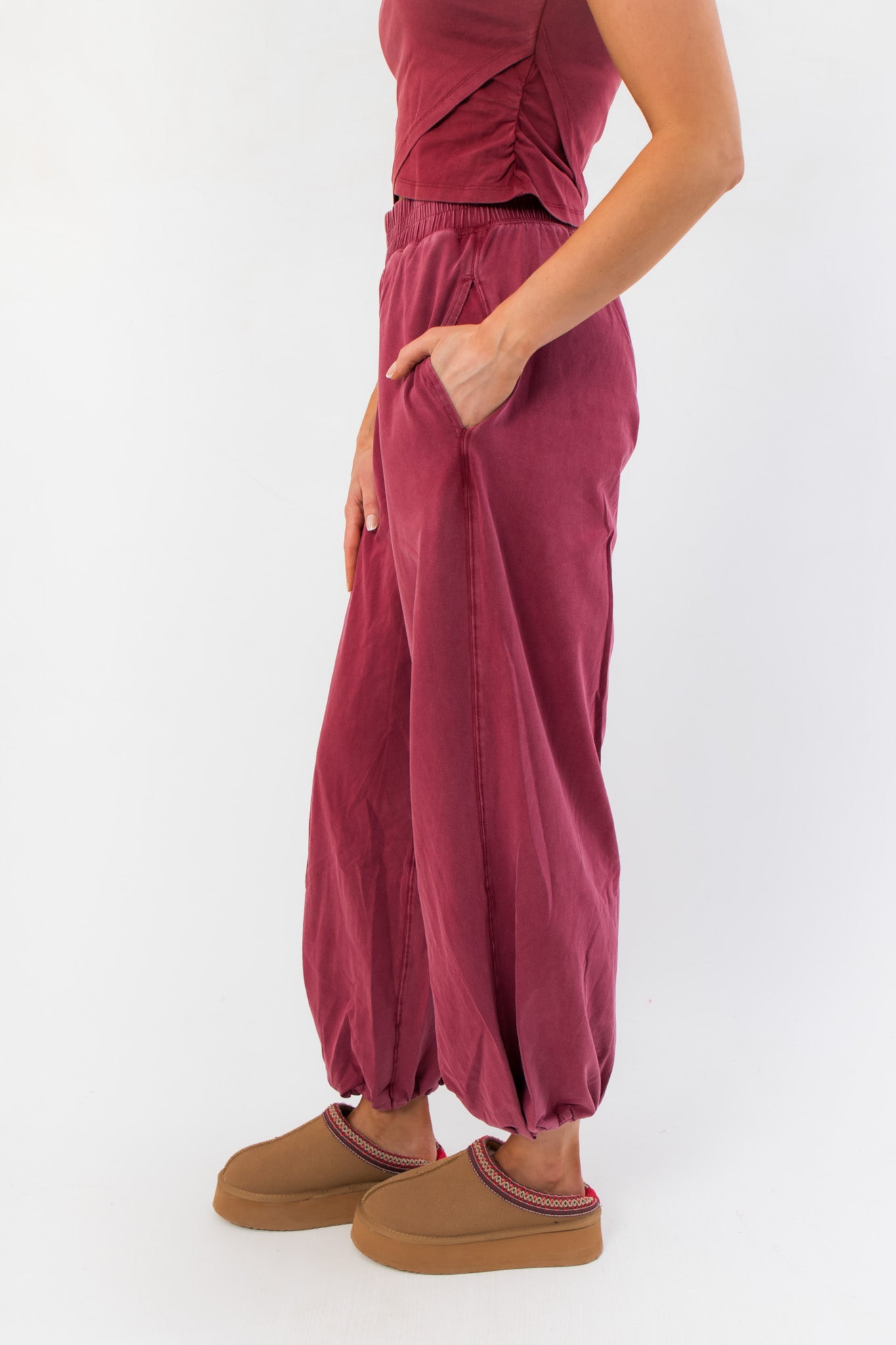 Side view of Winterberry Elastic Waist Jogger Sweatpants highlighting relaxed silhouette, deep pockets, and gathered ankle cuffs in berry red.