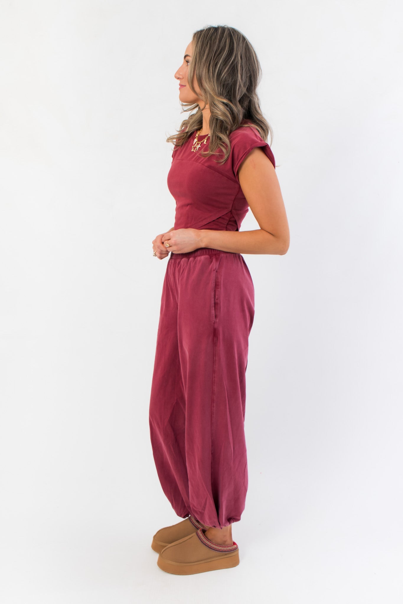Side view of Winterberry Short Sleeve Crop Top showing cropped length and rolled sleeves, styled with matching berry red joggers.