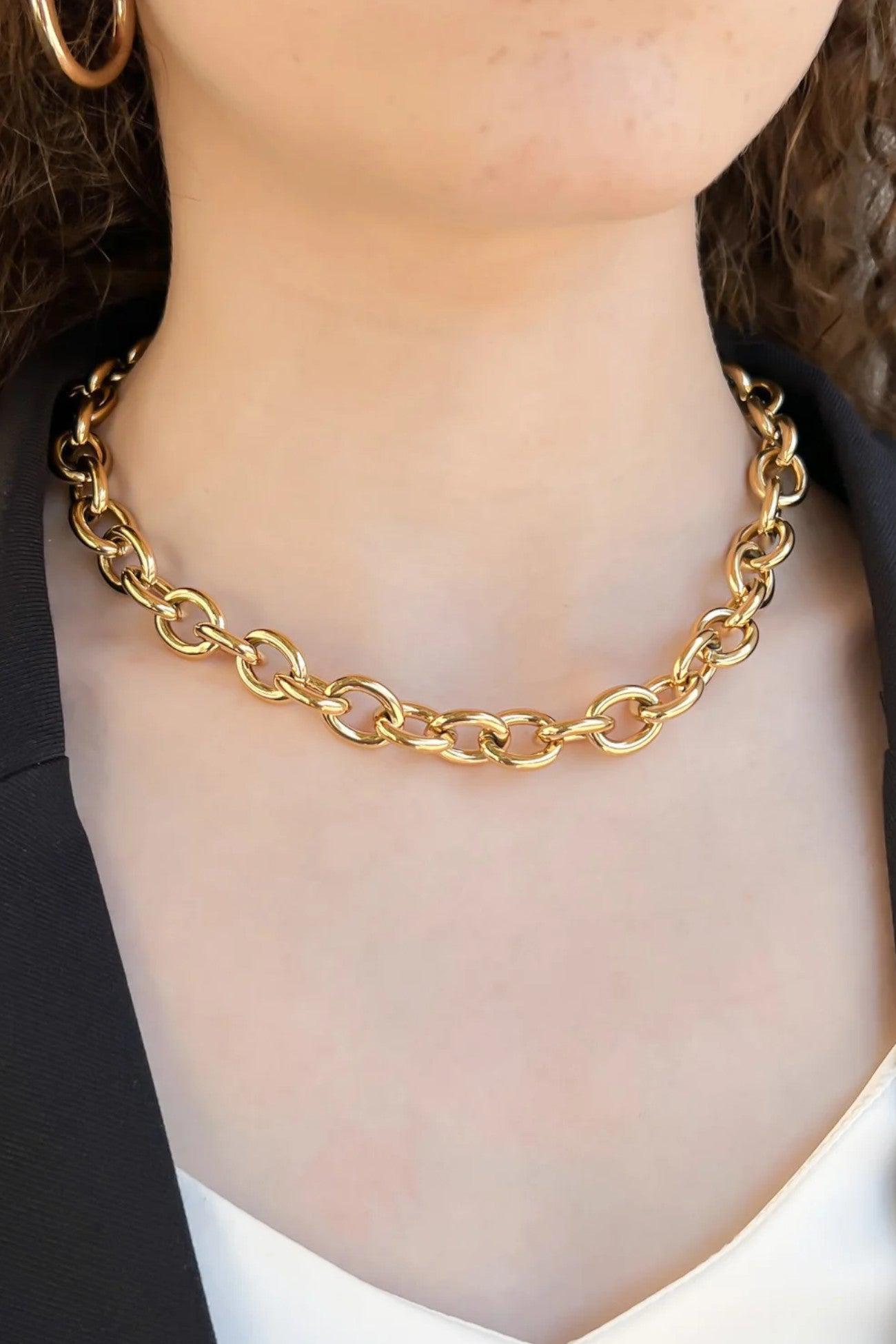 Ellie Gold Chunky Curb Chain Necklace worn by a model, showcasing its bold statement design. Triple-plated gold finish adds elegance to any outfit.