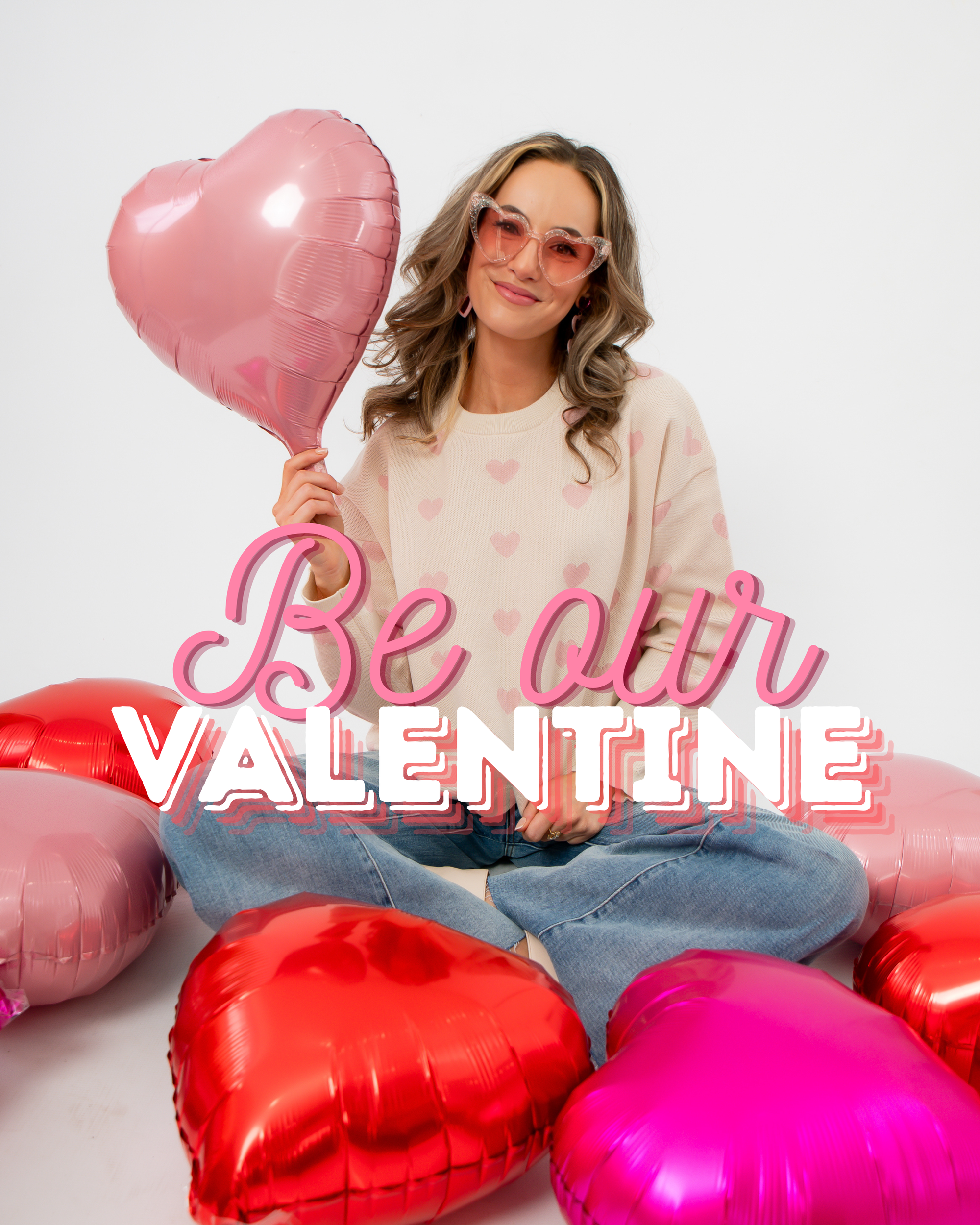 Woman holding a pink heart balloon with 'Be our VALENTINE' text and surrounded by heart-shaped balloons.