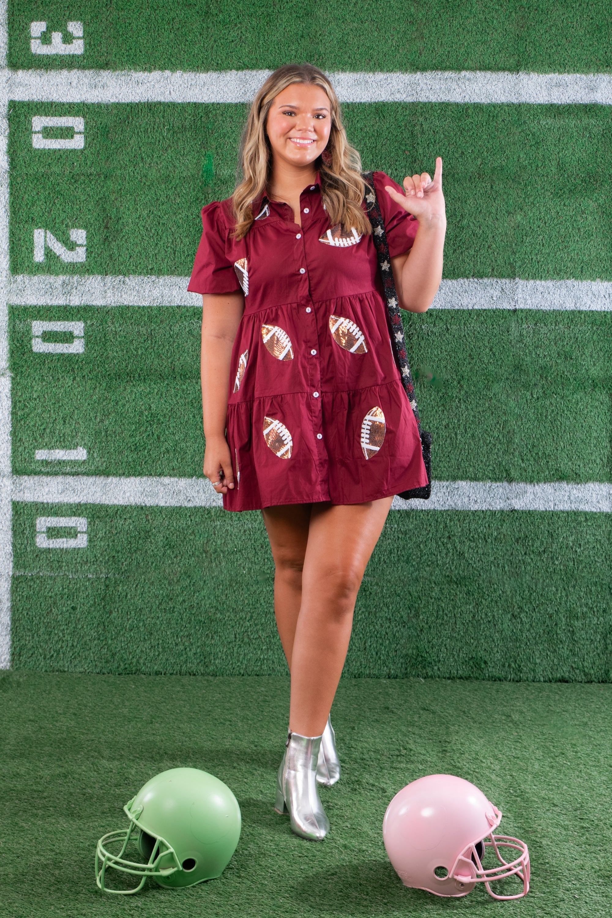 Shine in style with the Garnet Sequin Football Dress, a short-sleeve button-up mini dress featuring sequin football patches. Perfect for game day fashion.