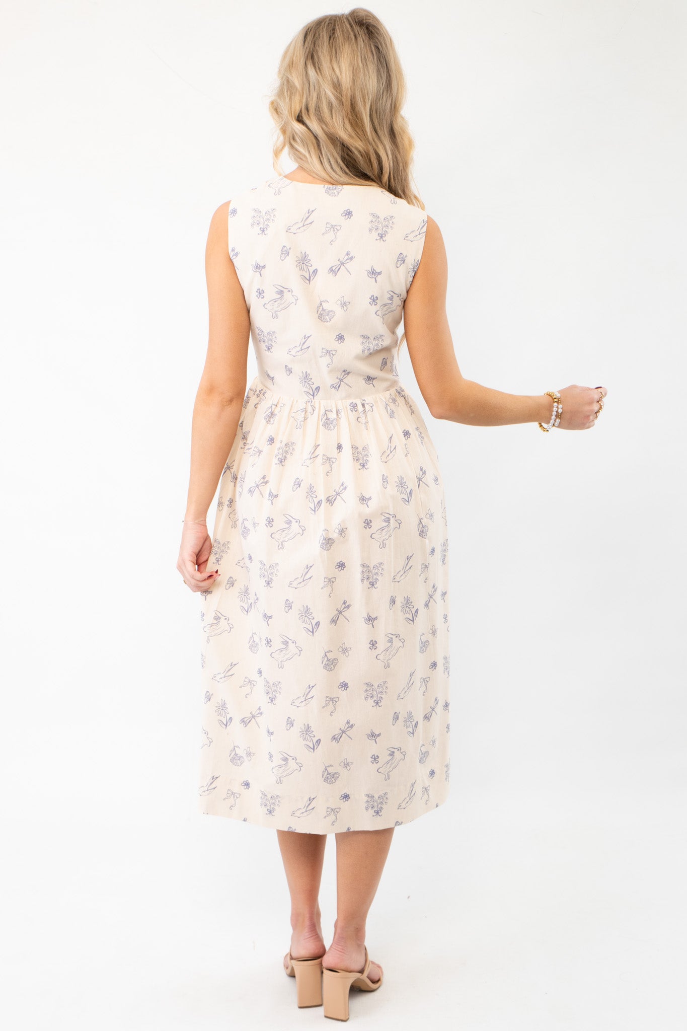 Back view of the Hop To It Beige Bunny Pattern Midi Dress, highlighting its sleeveless design, gathered waist, and charming bunny print.