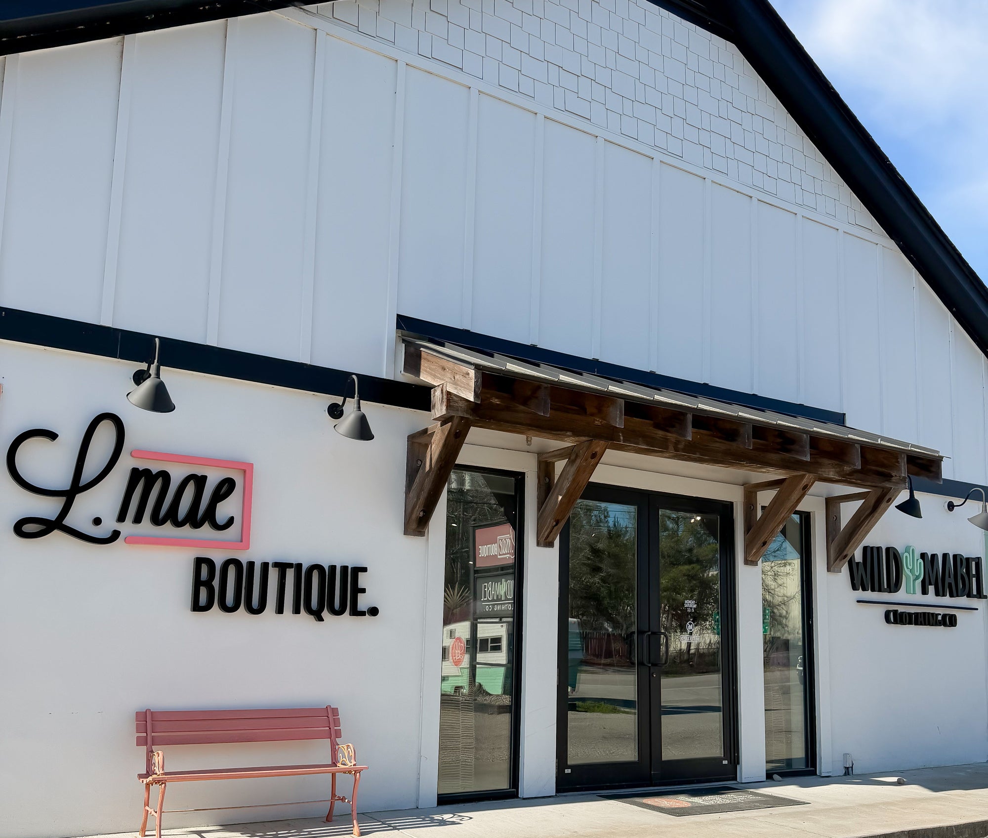 L.mae Boutique building with a bench in front on a clear day