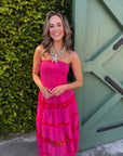 Woman wearing bright pink strapless dress with starfish and seashell necklace outdoors