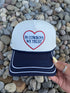 White trucker hat with navy brim and embroidered heart with 'In Cowboys We Trust' text