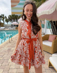 Paloma Please Scallop Appliqué Sleeveless Dress in rust orange floral, styled poolside with scalloped trim and waist tie, ideal for summer events.