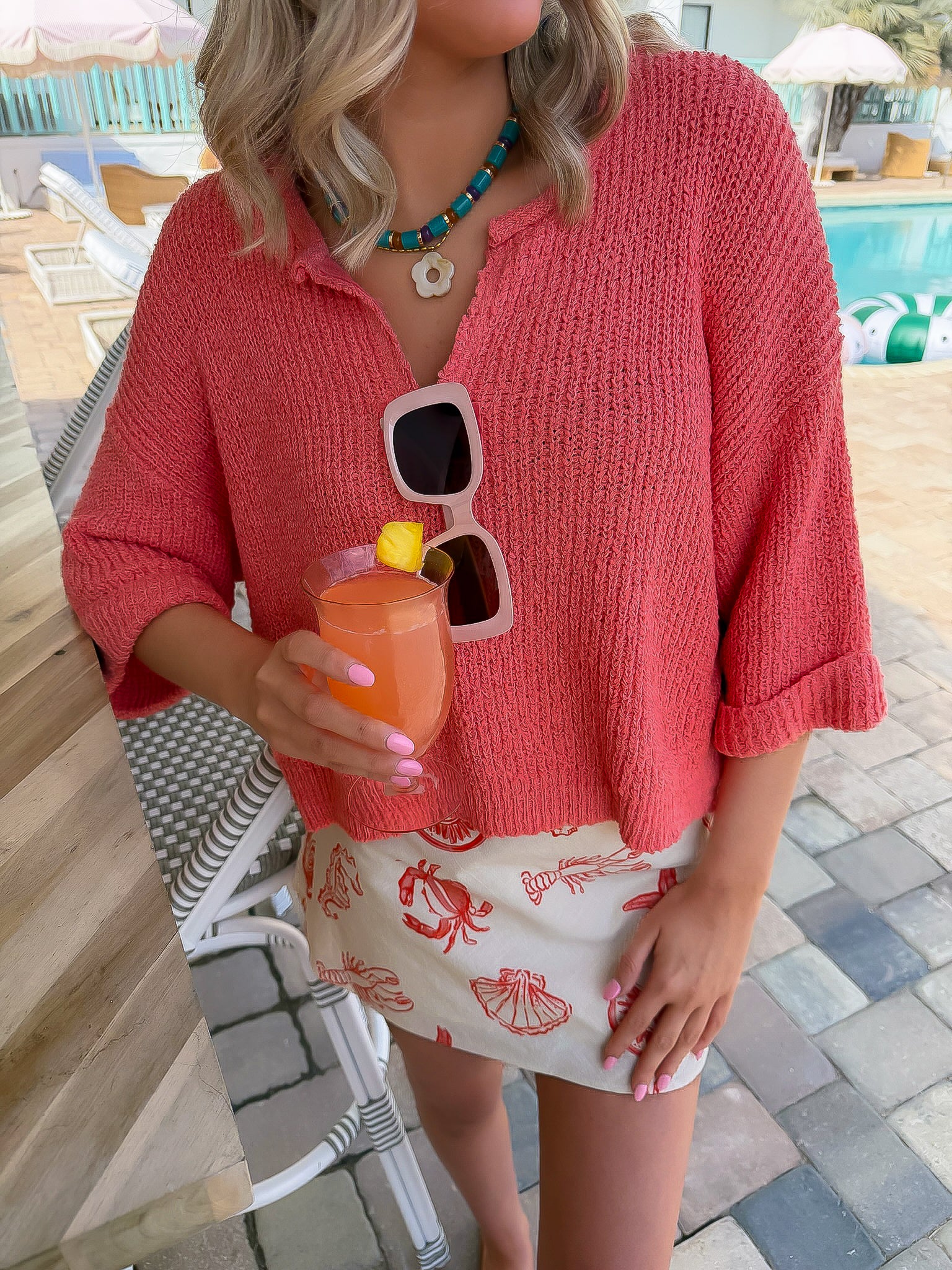Papaya Short Sleeve Crop Sweater | Lightweight Cropped Knit styled with a beach-themed mini skirt and drink by the poolside for summer fashion.