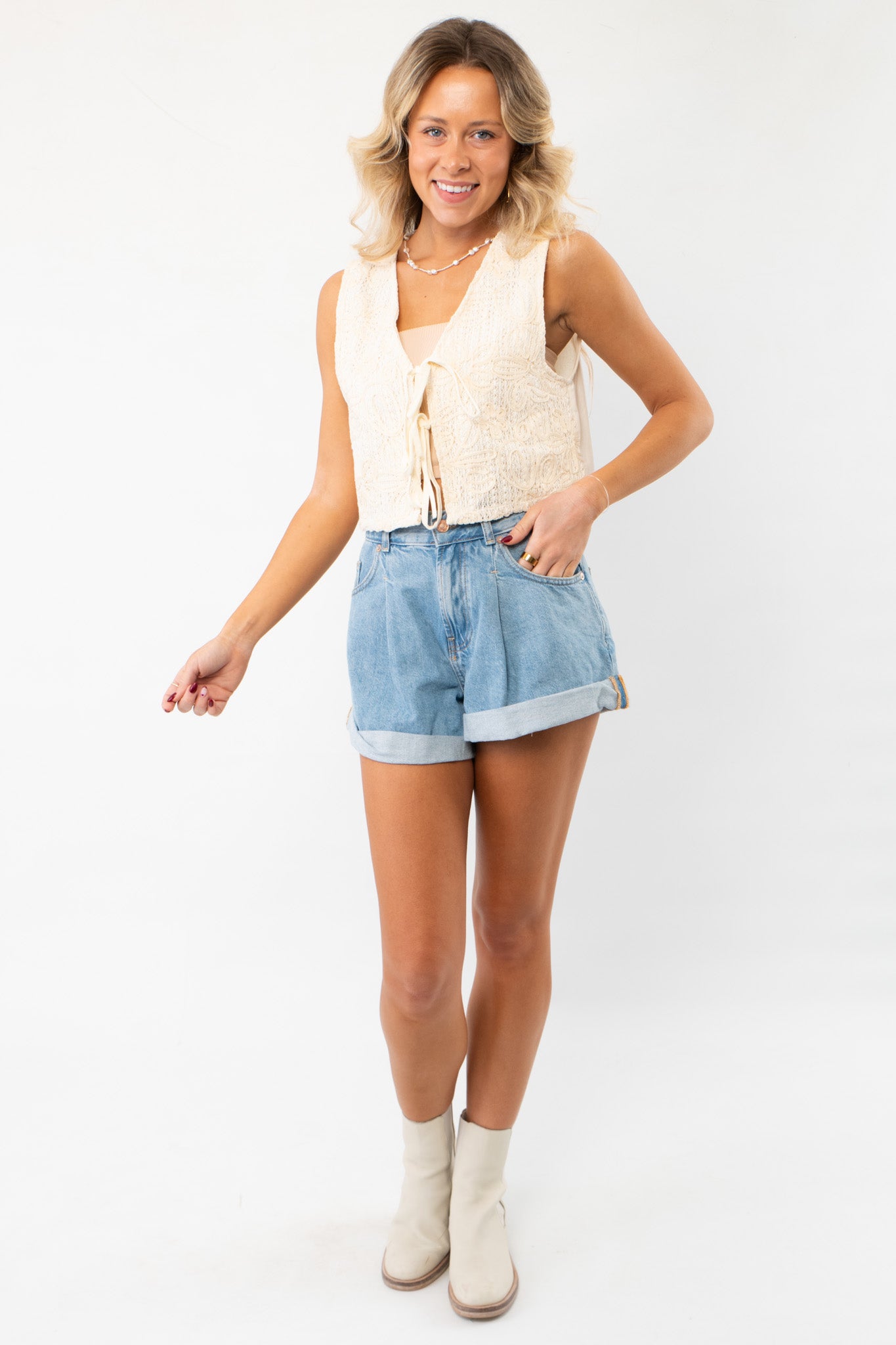 Model wearing the Jolene Beige Embroidered Tie Top Vest paired with denim shorts and ankle boots, showcasing a chic boho-inspired summer look.