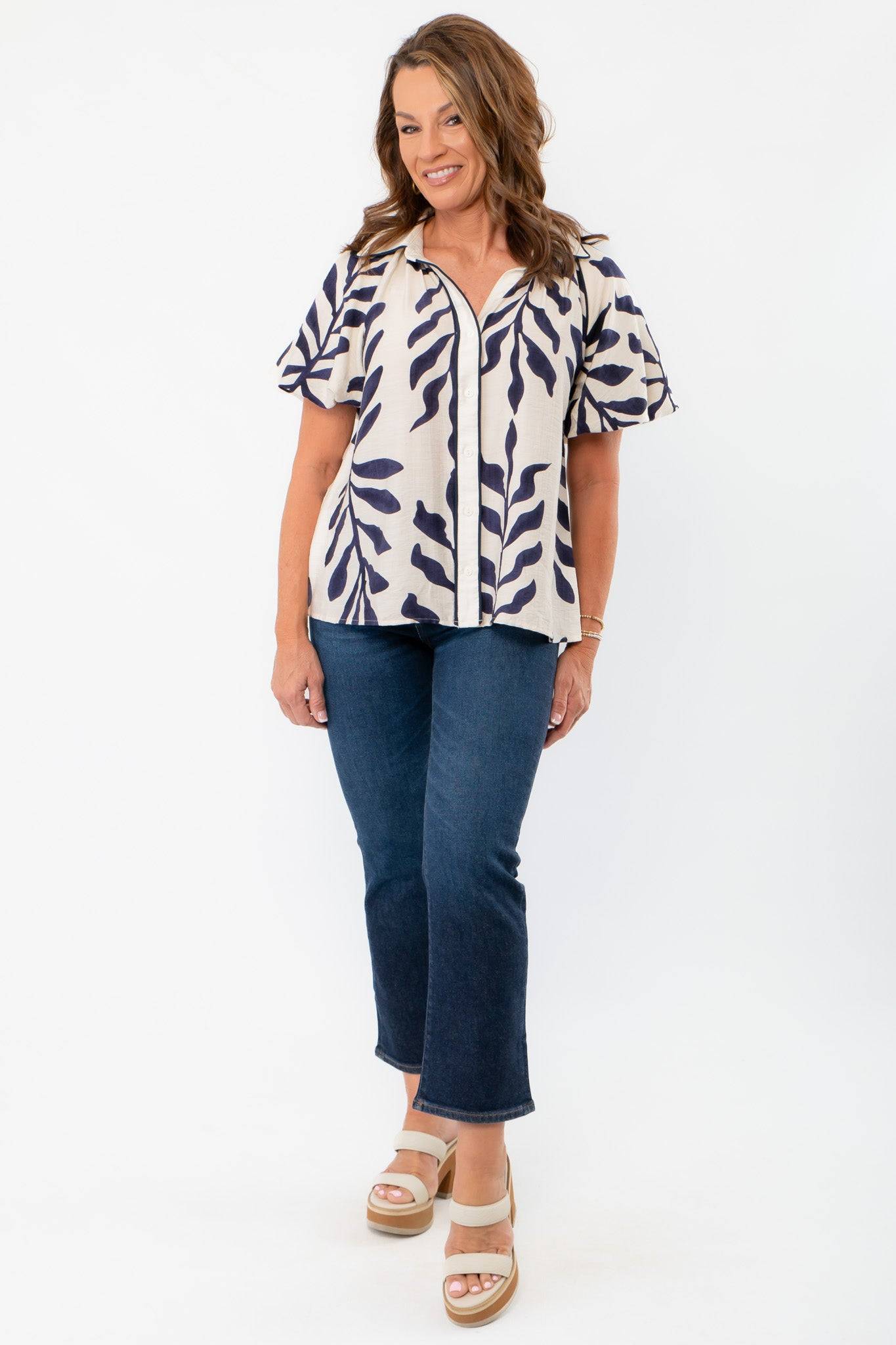 Navy Button Down Puff Sleeve Shirt paired with denim jeans, showcasing its relaxed fit and nature-inspired print for casual elegance.