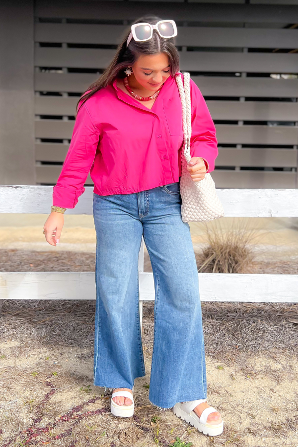 Model wearing Kut Adaptability Ryan High Rise Super Wide Leg Denim with a pink jacket and platform sandals, showcasing a trendy casual look.