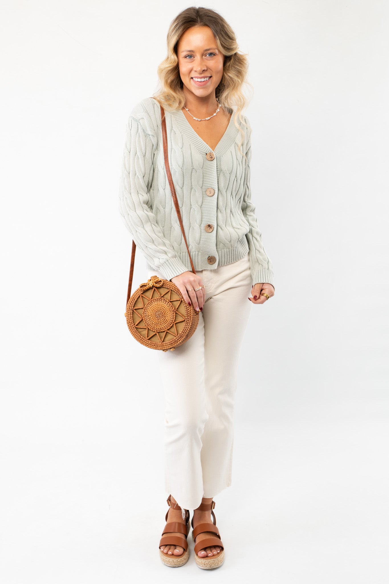 Chic Liza Mint Cable Knit Cardigan styled with neutral pants and a woven bag. A versatile and timeless layering piece for effortless fashion.