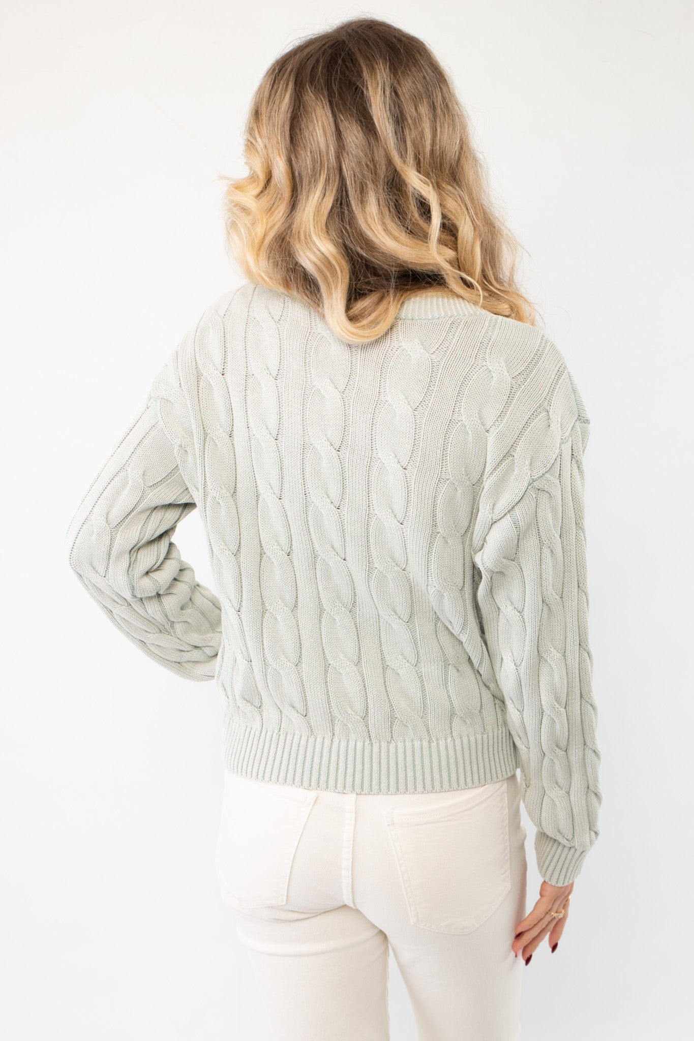 Back view of Liza Mint Cable Knit Cardigan highlighting its textured cable knit design and relaxed silhouette. A cozy and stylish wardrobe essential.