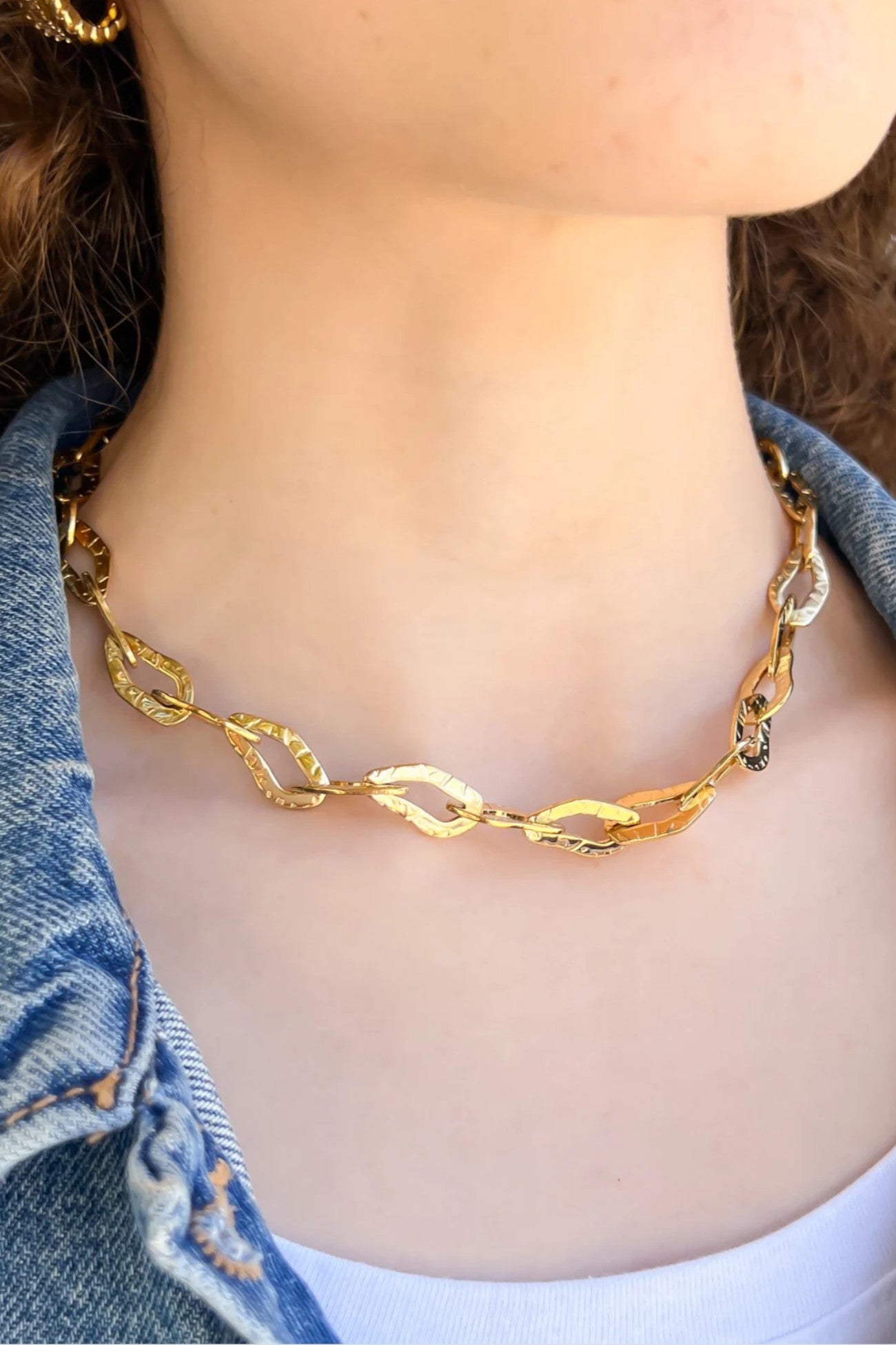 Lucy Gold Hammered Chain Necklace worn with a denim jacket, showcasing its modern elegance and water-resistant design.