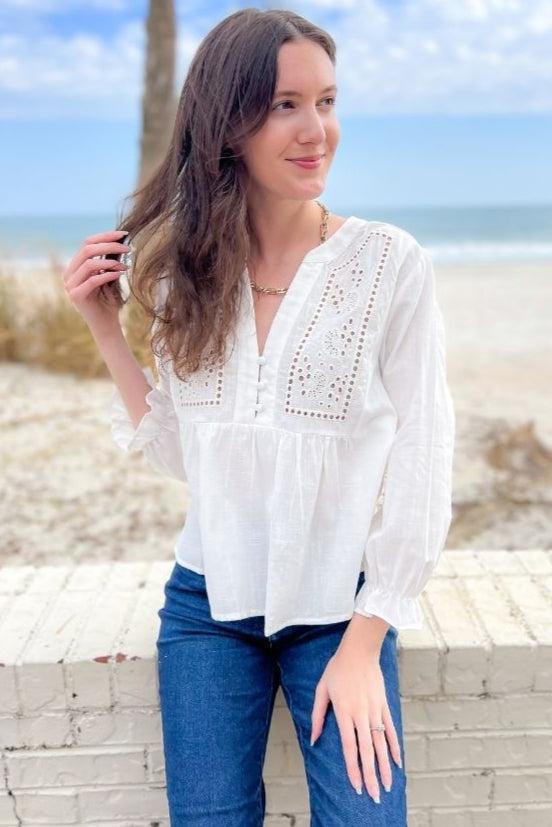 Boho-inspired Natalie White Eyelet Button Blouse featuring intricate embroidery, a V-neckline, and long sleeves. A versatile and elegant top for any occasion.