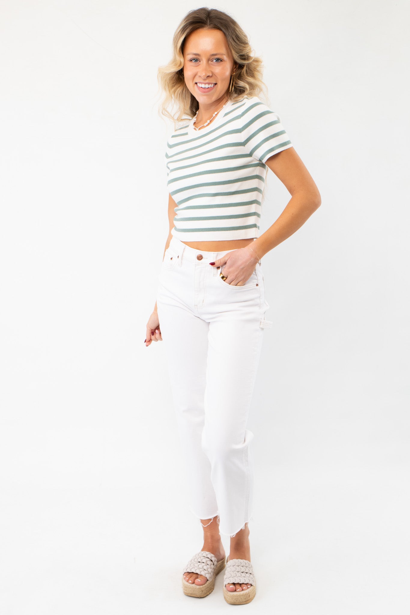 Trendy Next Up Green Striped Knit Crop Top styled with high-waisted white jeans and woven sandals for a casual summer outfit.