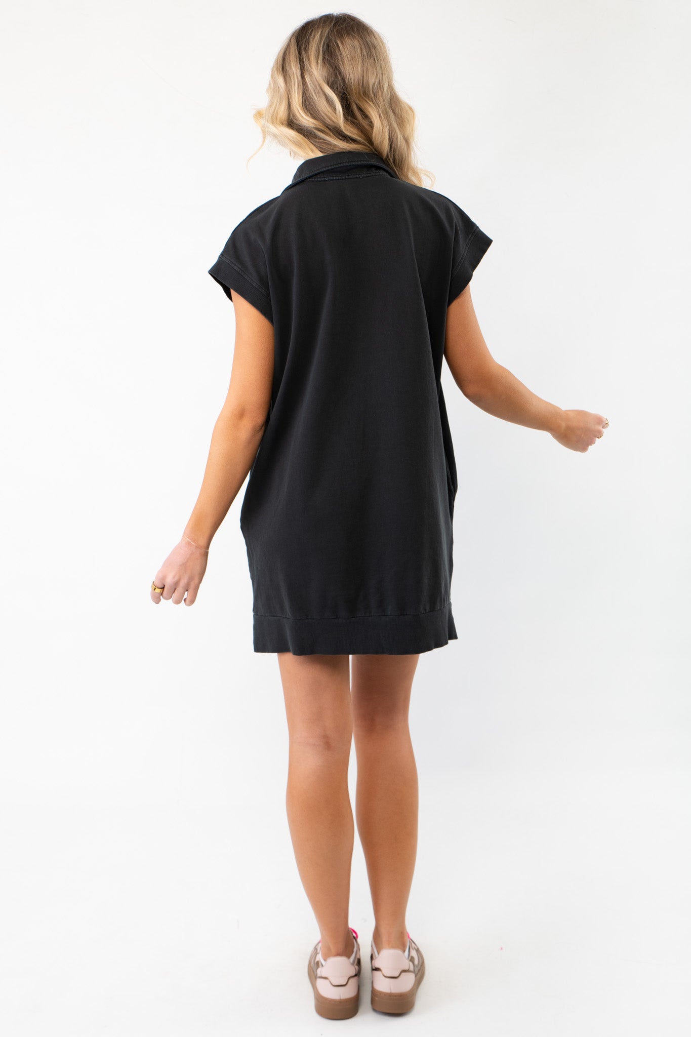 Back view of the On The Go Black Quarterzip Mini Dress, displaying its loose fit and casual design, ideal for a laid-back yet fashionable look.