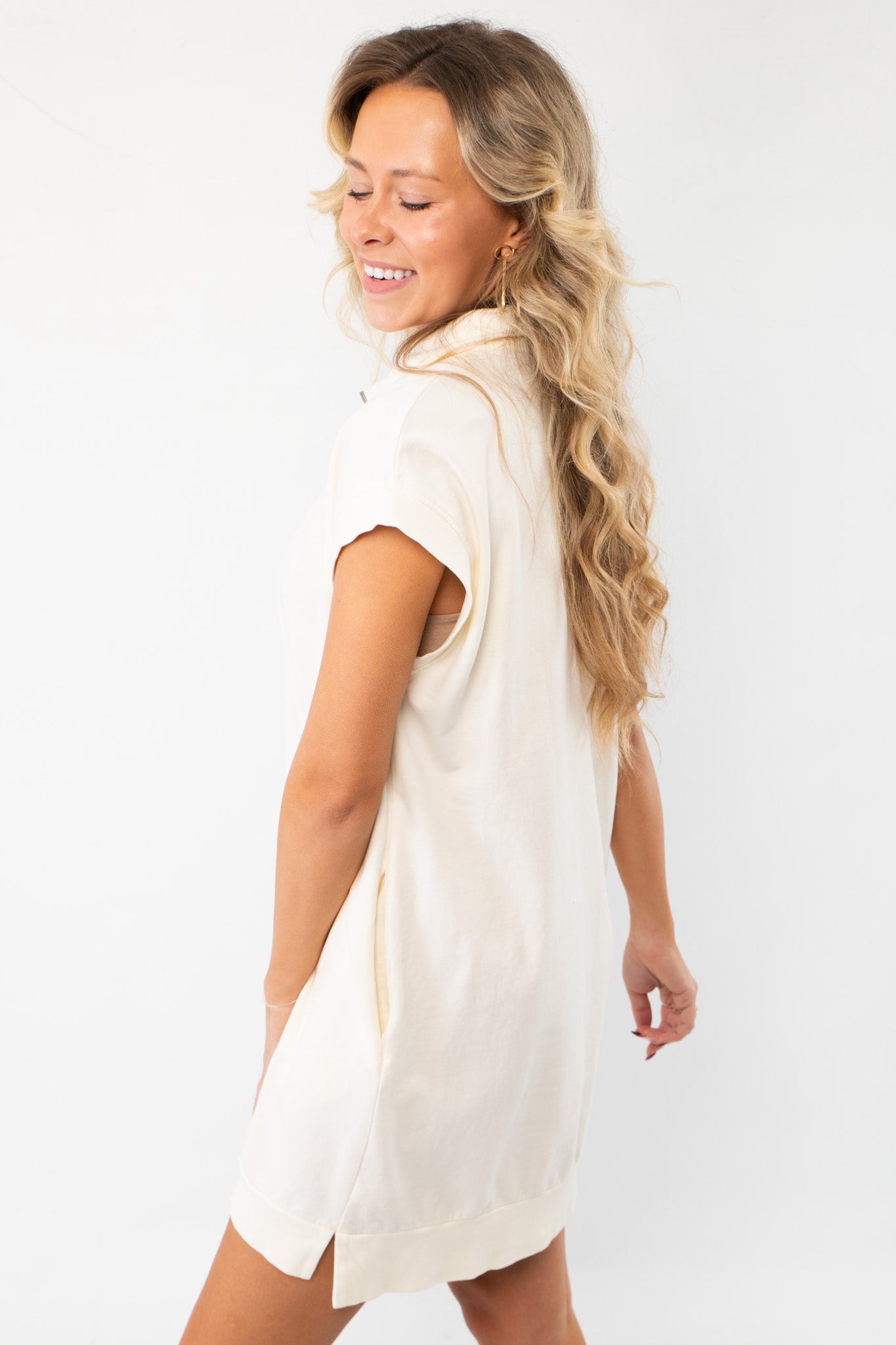 Back view of the On the Go Cream Quarterzip Mini Dress showcasing its soft fabric, relaxed fit, and subtle side slits for added comfort.