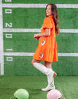 Game day ready in the Orange Sequin Football Dress, a stylish mini dress with a relaxed fit, football sequin embellishments, and short sleeves.