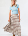 Model wearing Fort Worth Brown Plaid Maxi Skirt with light blue top and cowboy hat, showcasing western-inspired fall style.