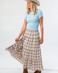 Side view of Brown Plaid Maxi Skirt - Fort Worth paired with a blue tee and boots, highlighting its flowing tiered silhouette.