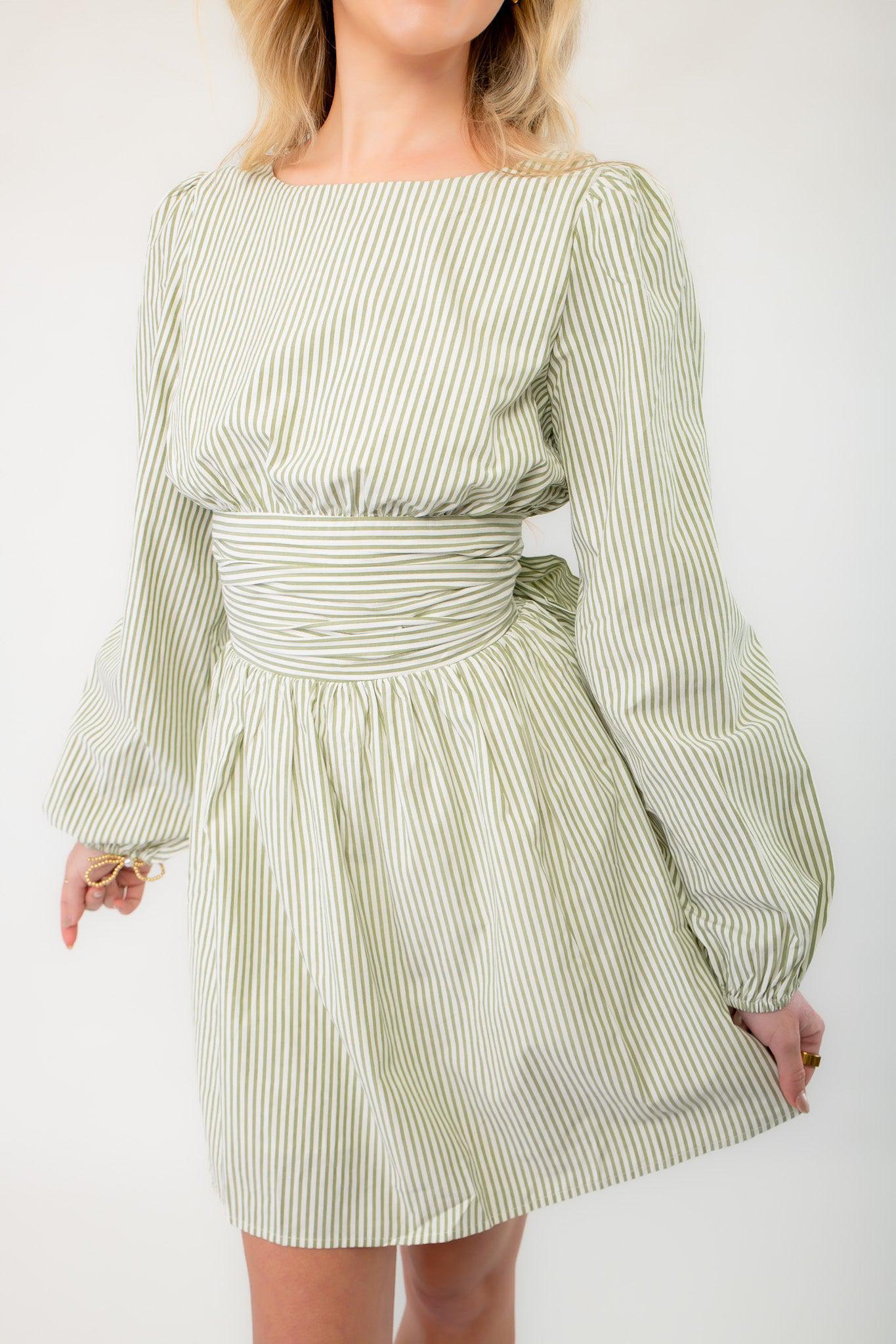 Close-up of sage striped mini dress with a cinched waist and balloon sleeves, showcasing its lightweight fabric and flattering fit for spring fashion.