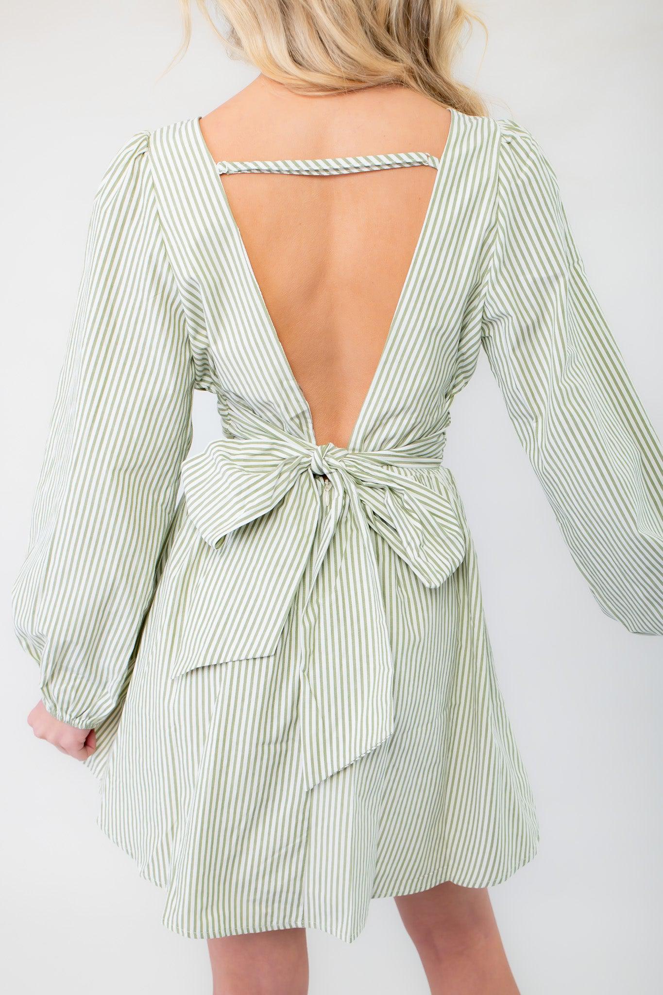 Back view of sage striped mini dress highlighting its open-back design with a bow tie detail, adding a stylish and feminine touch to the outfit.