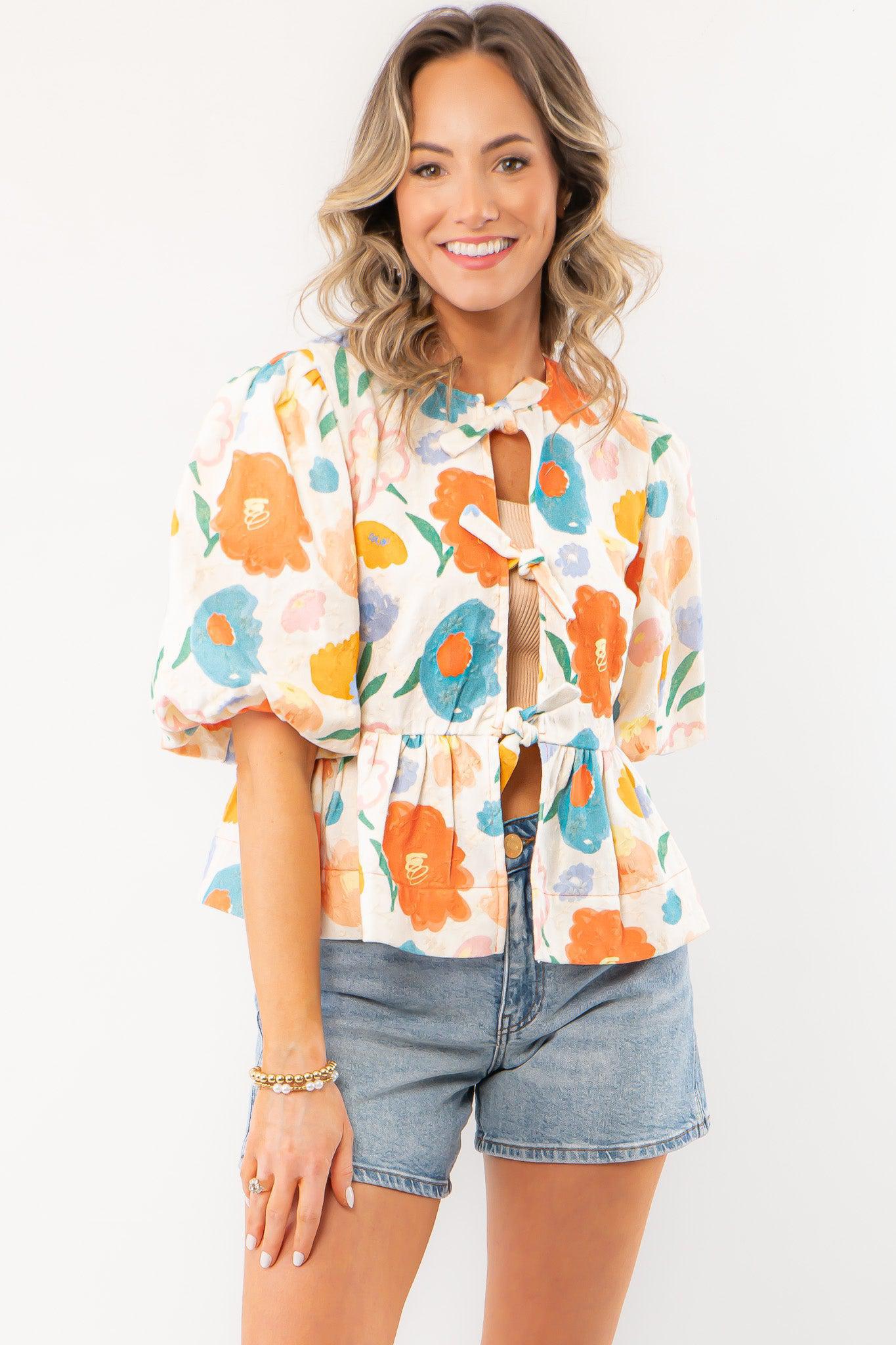 Spring Floral Tie-Front Top with bright floral prints, puff sleeves, and a peplum hem, styled with denim shorts for a fresh spring look.