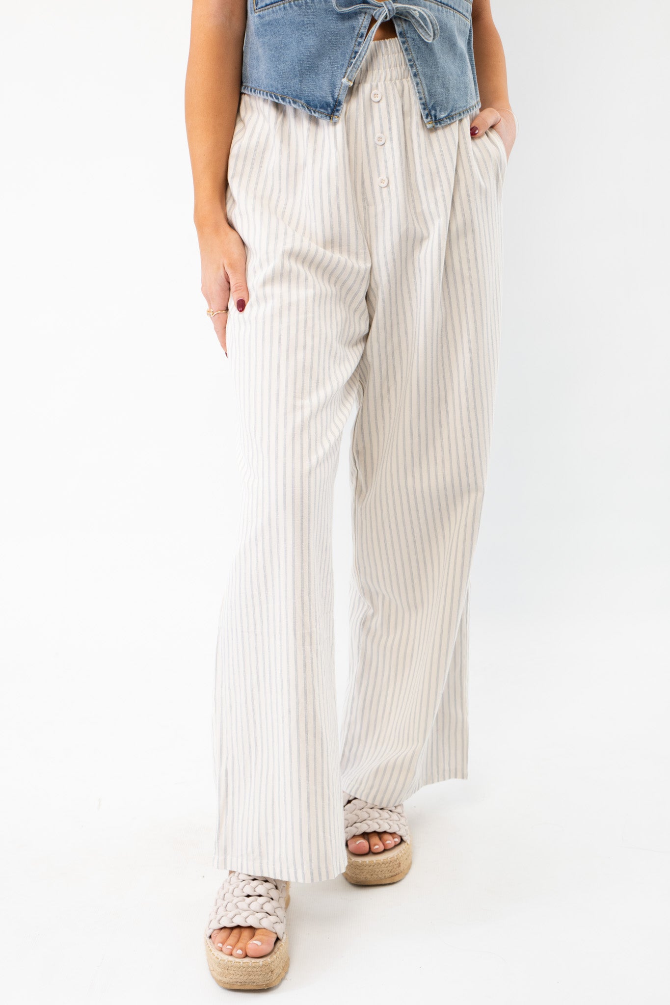 Sullivan Striped Boxer Linen Pants in cream and blue stripes, featuring a high-waisted elastic fit with button details, styled with a denim crop top.