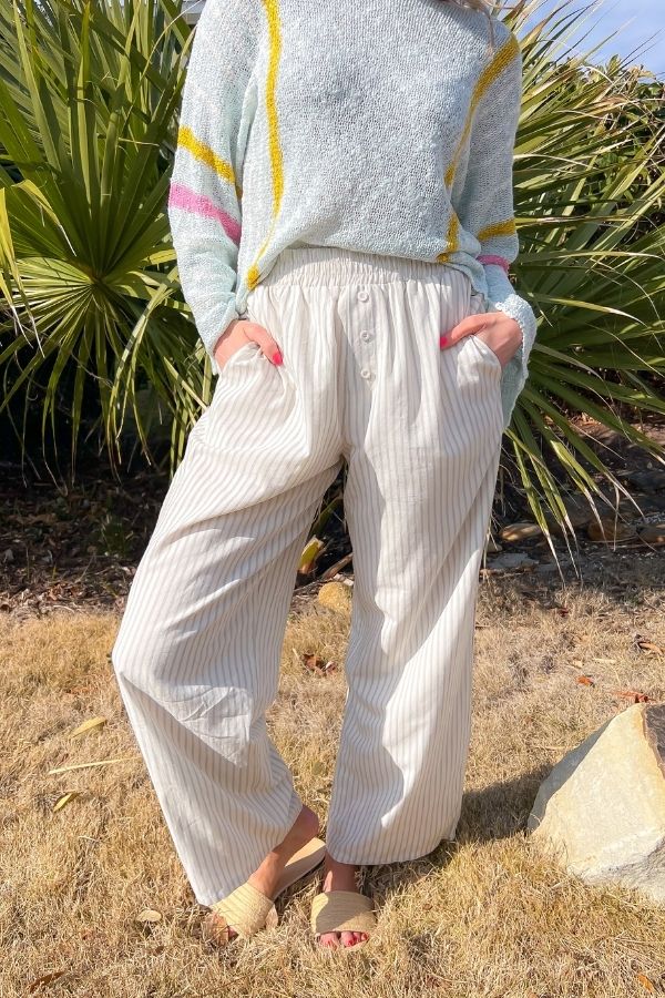 Sullivan Striped Boxer Linen Pants with a relaxed fit, elastic waist, and button details, styled with a lightweight sweater for a breezy summer look.