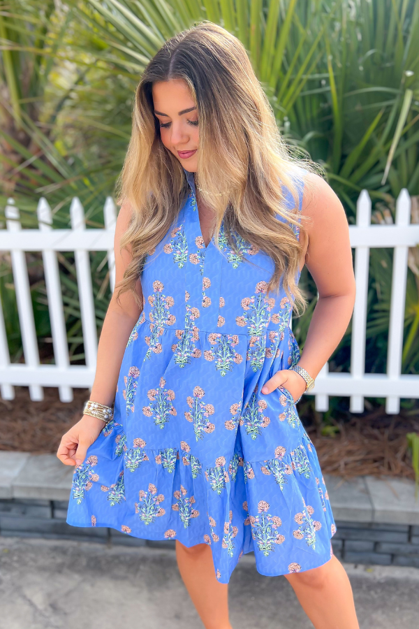 THML Blue Floral Sleeveless Tiered Mini Dress with a vibrant floral print, V-neckline, and playful collar. Perfect for spring and summer styling.