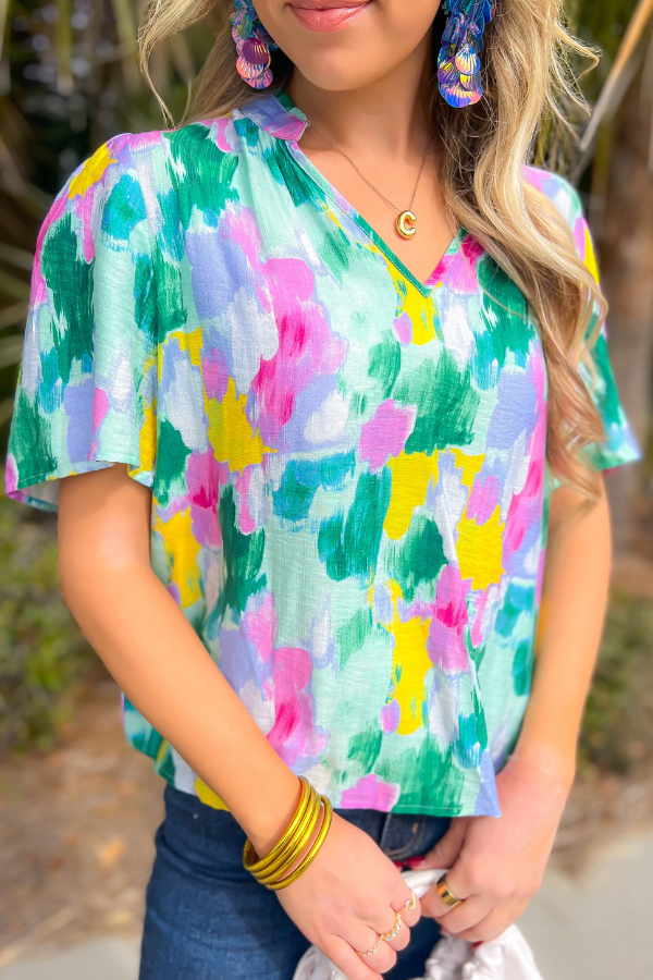 Close-up of THML Aqua Abstract Blouse showcasing lightweight fabric, colorful abstract pattern, and v-neck detail for a chic spring look.