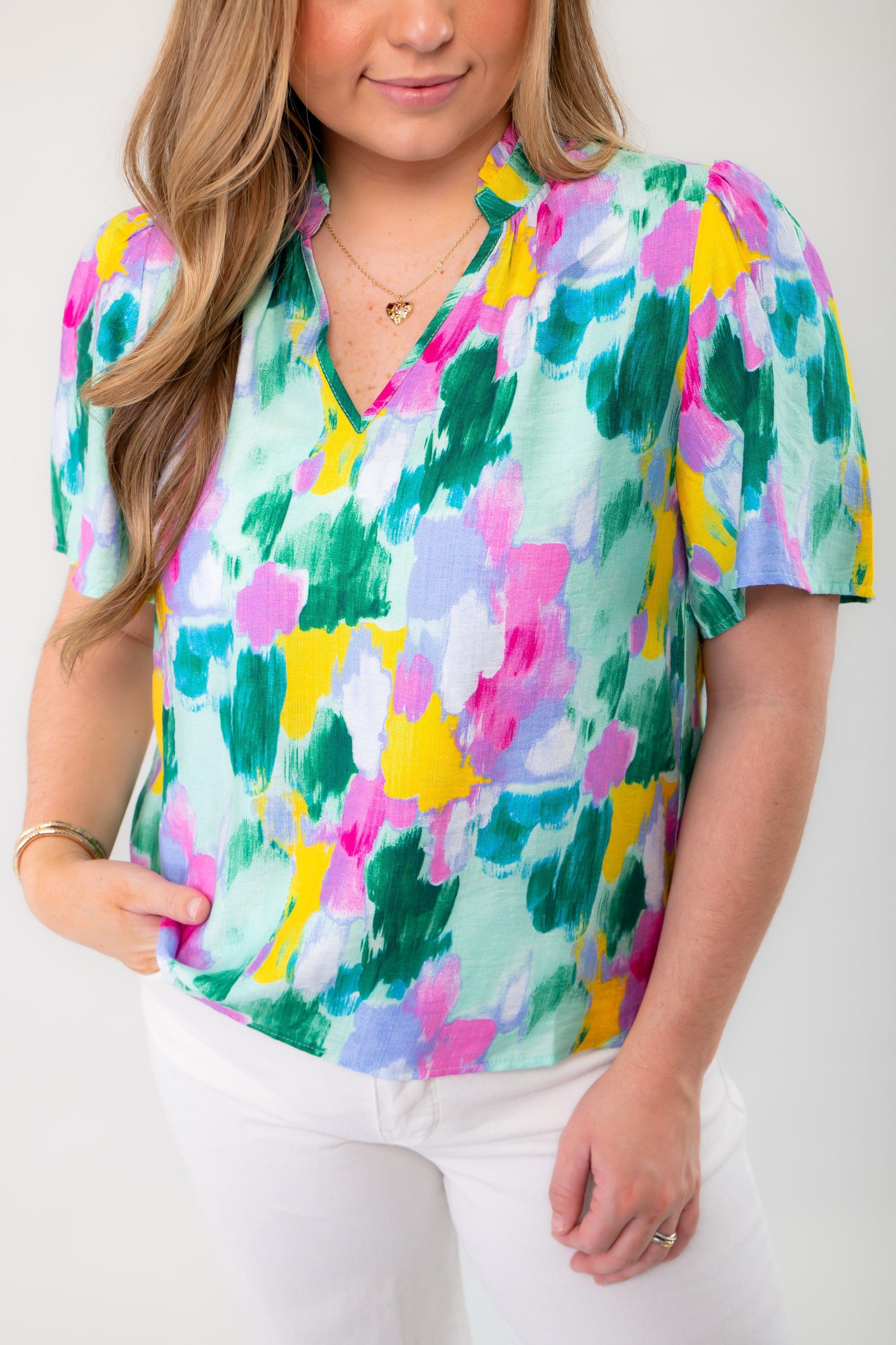 Detailed front view of THML Aqua Abstract Blouse highlighting its colorful print, v-neckline, and short sleeves, perfect for warm-weather outfits.