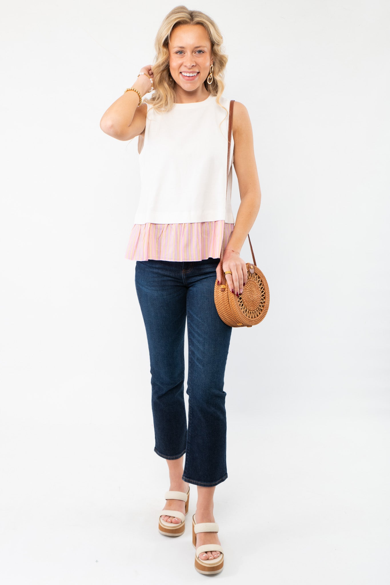 Model wearing The Fun Of It White & Pink Tank Top paired with dark jeans and a woven bag, showcasing a trendy spring outfit.