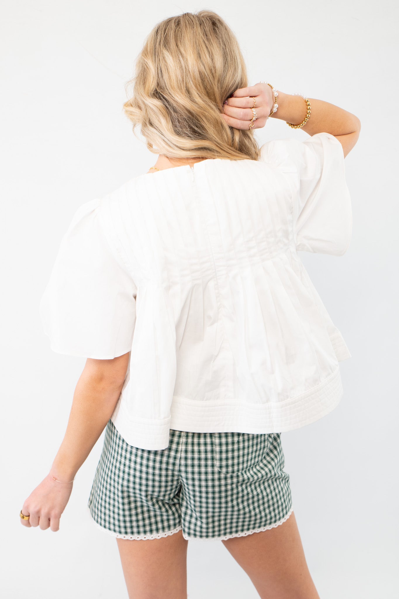 Back view of the In This Moment Ivory Pleated Blouse, highlighting its structured pleats and relaxed fit for a breezy summer outfit.