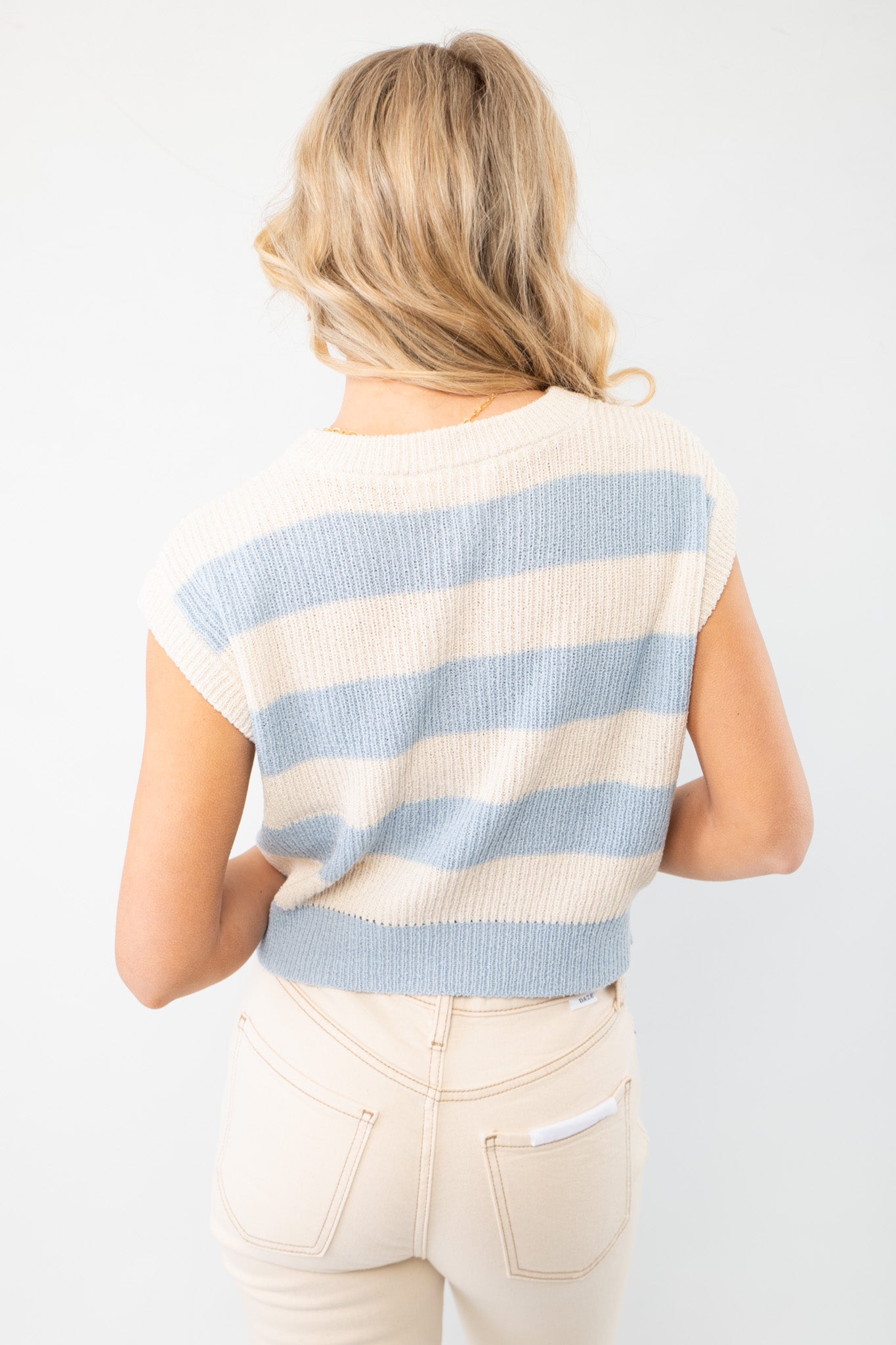 Back view of the Tyler Blue Striped Knit Cropped Vest, showcasing its relaxed fit, ribbed hem, and pastel blue and cream stripes for a chic seasonal outfit.