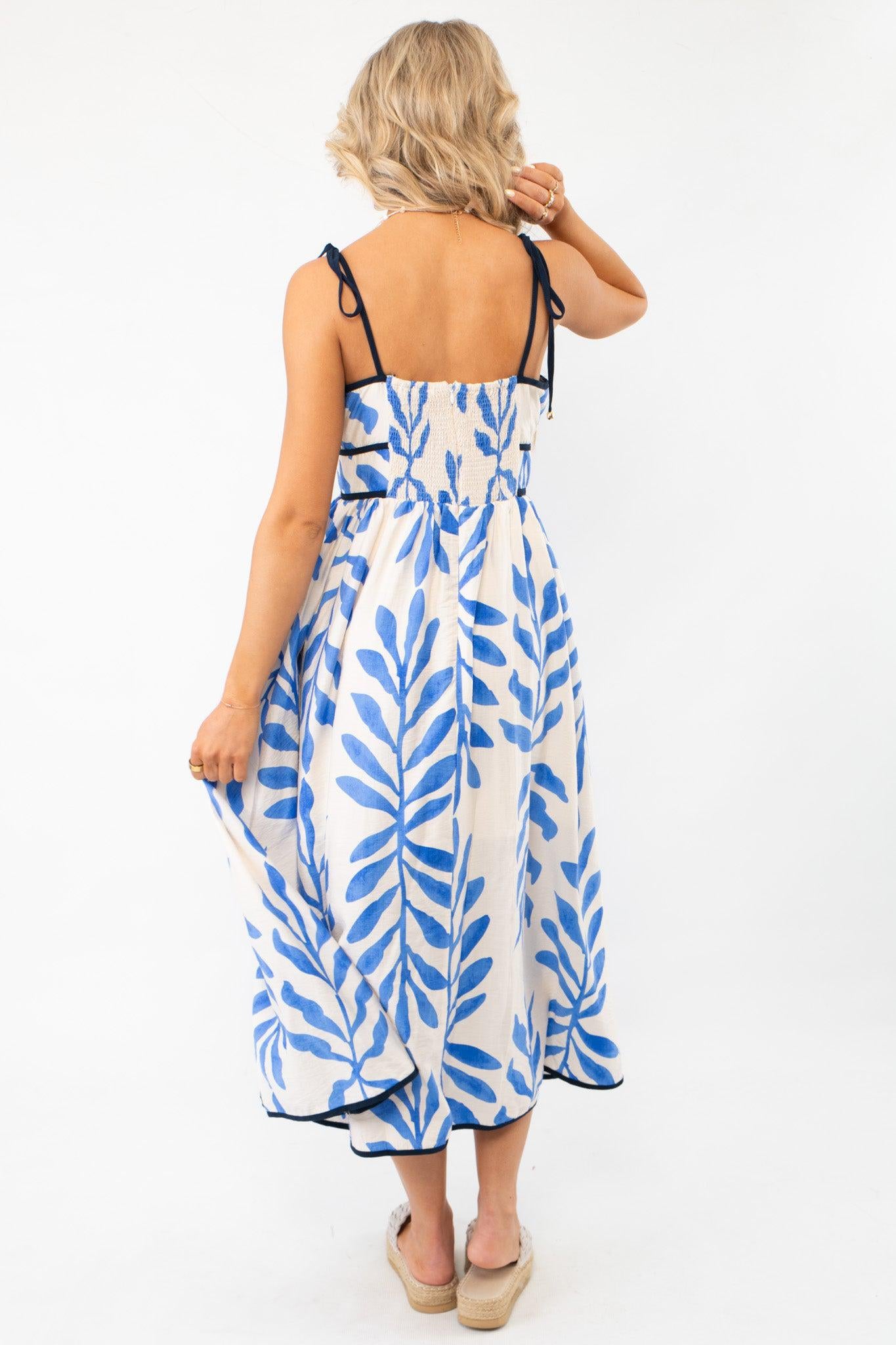 Back view of the Warmer Days Blue Floral Midi Dress featuring a smocked back and zipper for a comfortable fit.