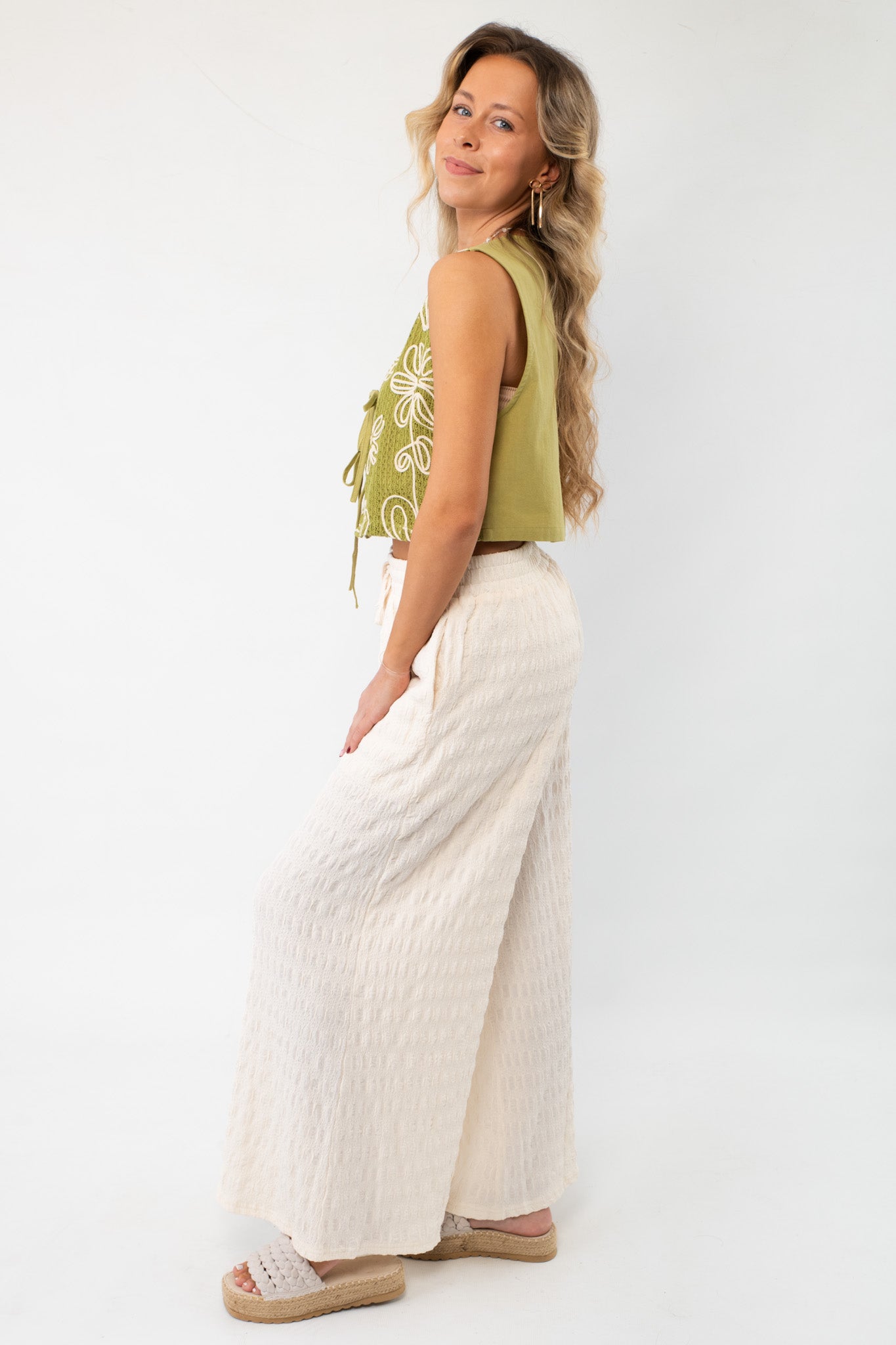 Side view of cream wide-leg knit pants with a wavy texture, highlighting their flowy silhouette and comfortable fit.