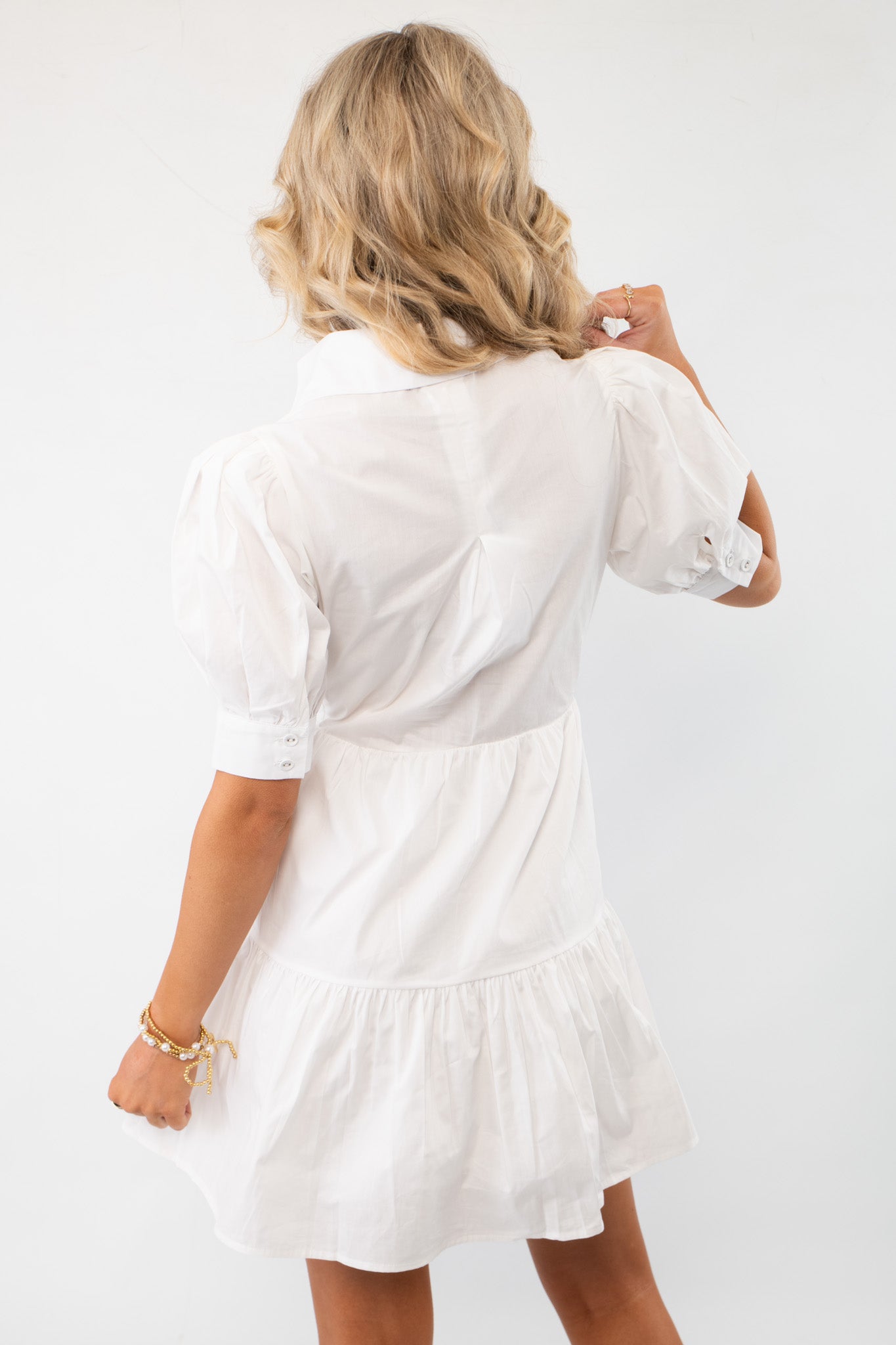 Back view of the White Lolita Bow Poplin Mini Dress, showcasing its lightweight fabric, puff sleeves, and tiered skirt. A perfect blend of elegance and comfort.