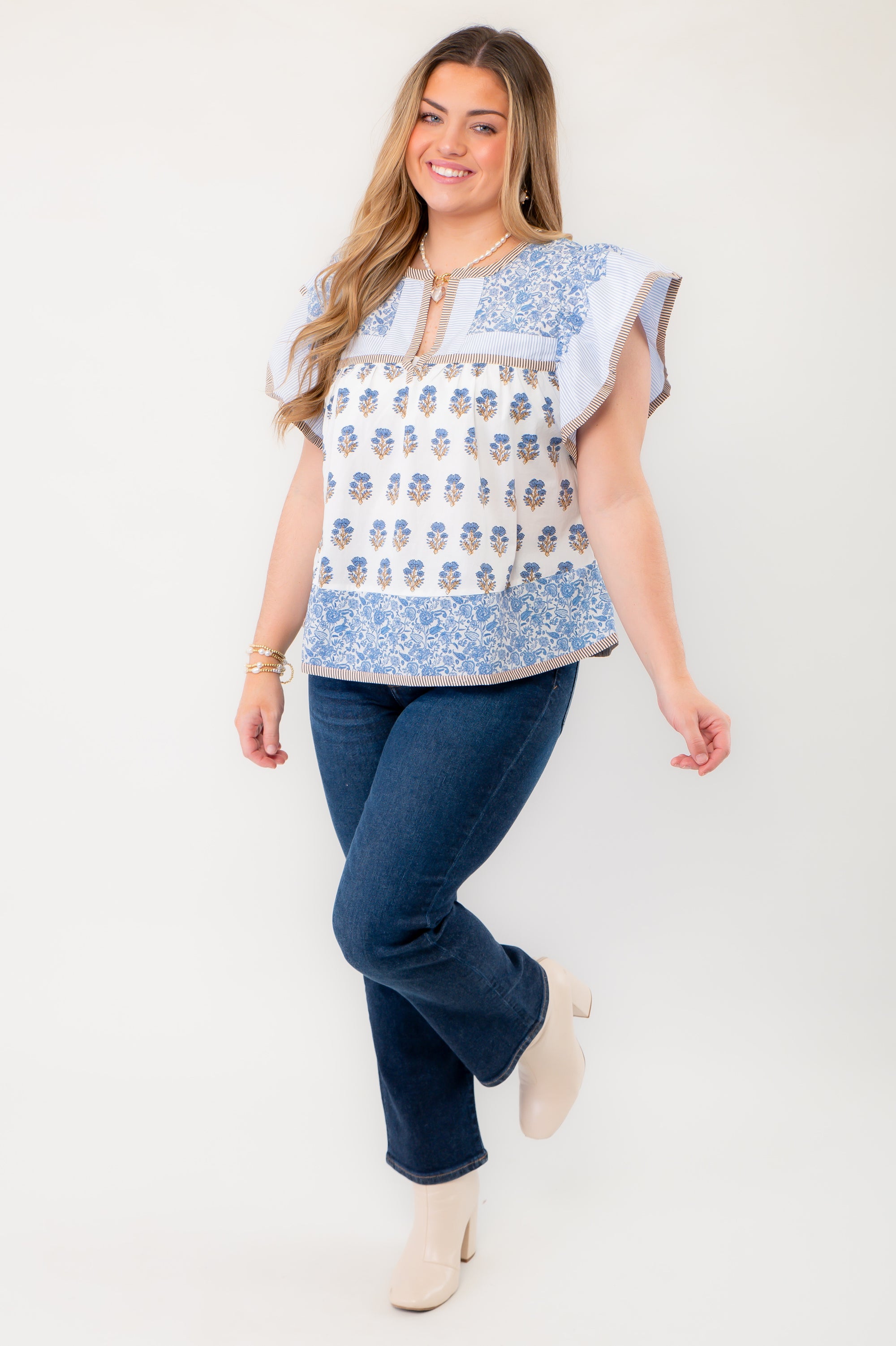 Full-body view of the Wildflower Ivory &amp; Blue Printed Ruffle Sleeve Top paired with dark denim and ankle boots, perfect for a chic spring outfit.